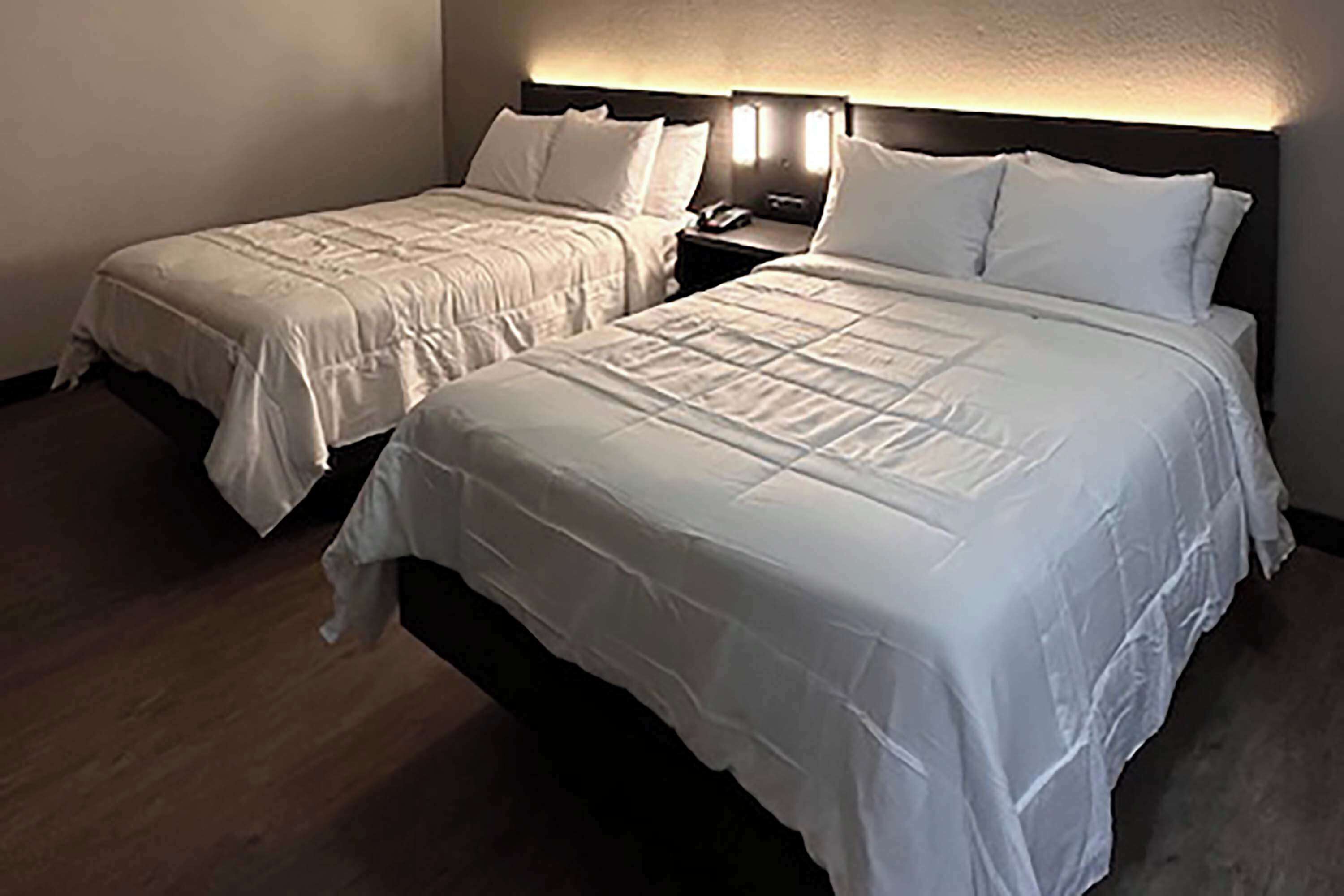 Dos camas individuales con ropa blanca en una habitación de hotel.