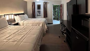 Habitación de hotel con dos camas, un televisor y un escritorio.