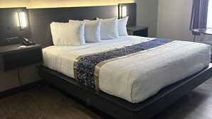A modern hotel room with a large bed, bedside lamps, a nightstand, and a wooden floor. - Baymont by Wyndham Deming (Deming)