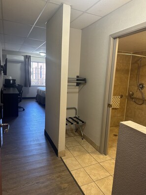A hotel room with a shower, a desk with a chair, and a window with curtains. - Baymont by Wyndham Deming (Deming)