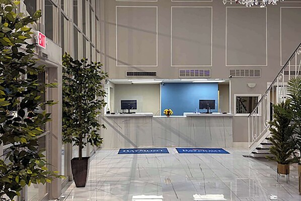 A reception area with a blue counter, two monitors, and a potted plant. - Baymont by Wyndham Deming (Deming)