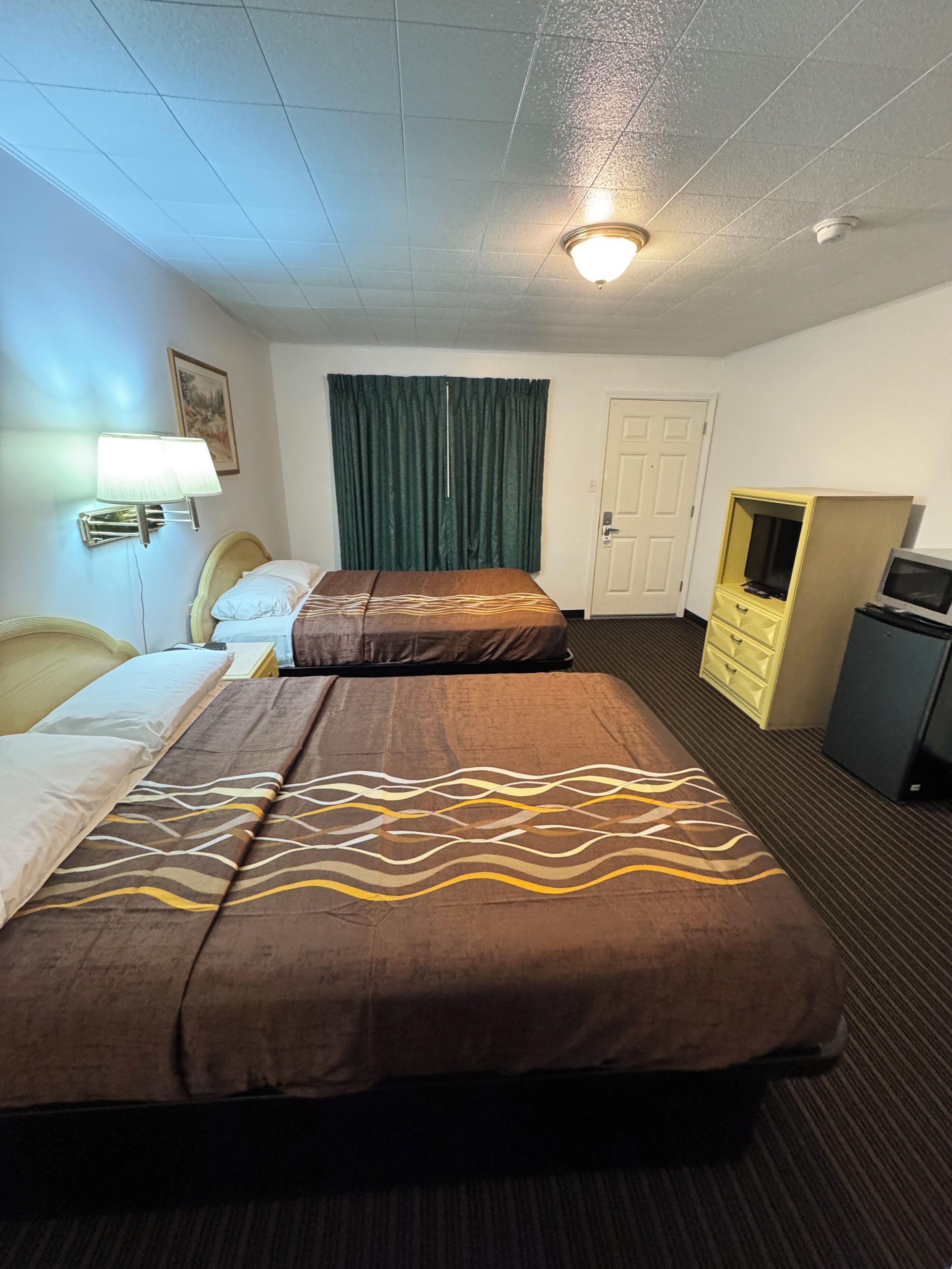 A hotel room with two beds, a desk, a television, and a wardrobe.