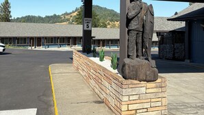 A building with a speed limit sign, a statue, and a parking lot. - Motel Garberville (Garberville)