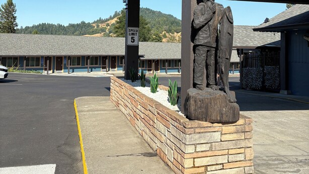 A building with a speed limit sign, a statue, and a parking lot.