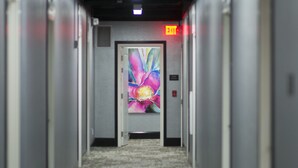 Un couloir qui se termine par une porte, au-dessus de laquelle est accrochée une peinture abstraite aux couleurs vives.