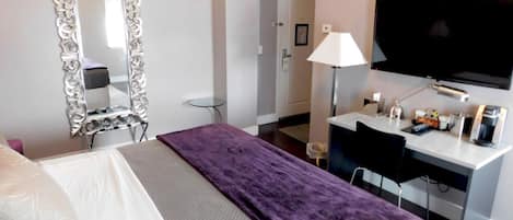 Habitació d'hotel amb llit, escriptori, televisió i mirall.