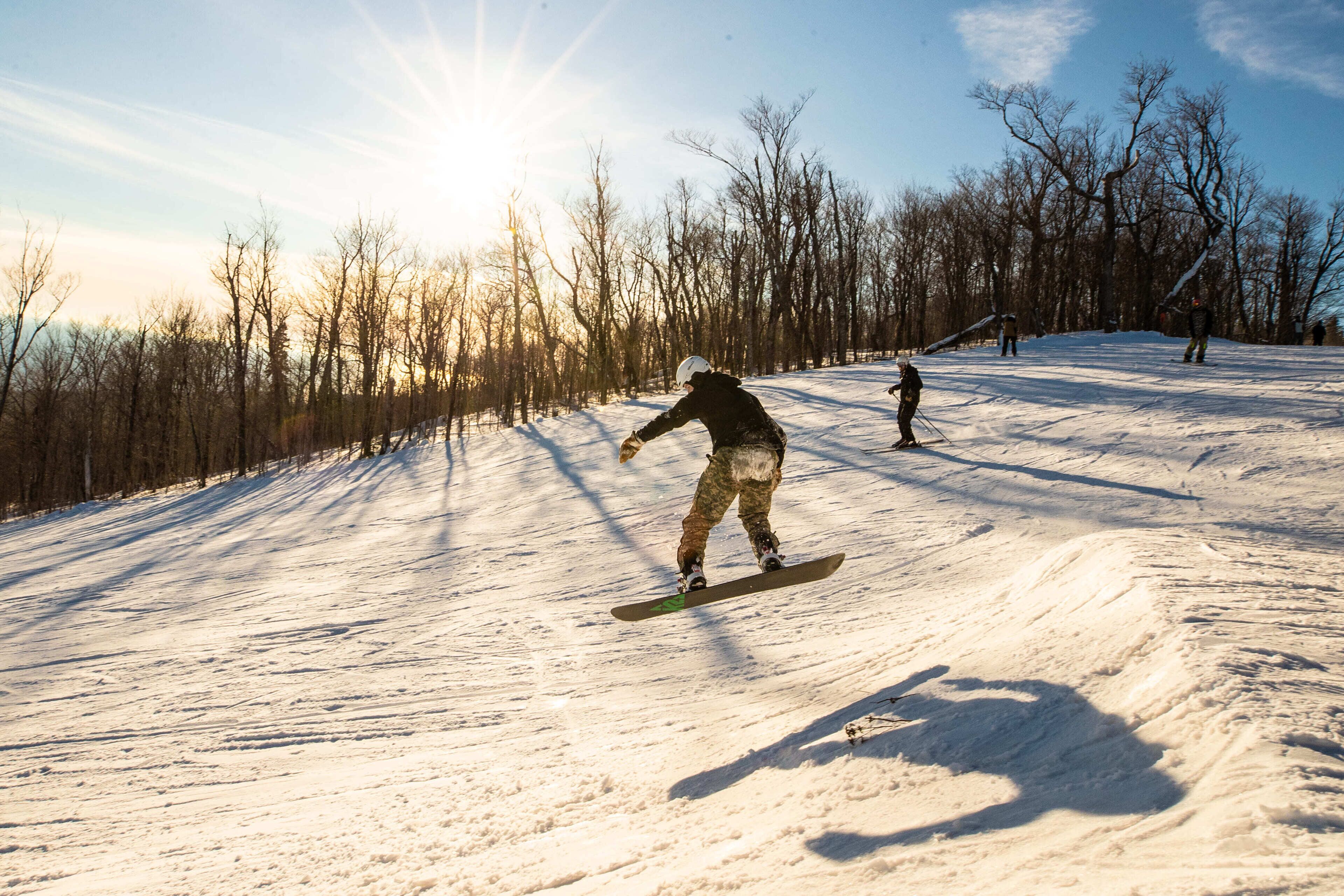 A snowy slope with skiers and snowboarders.