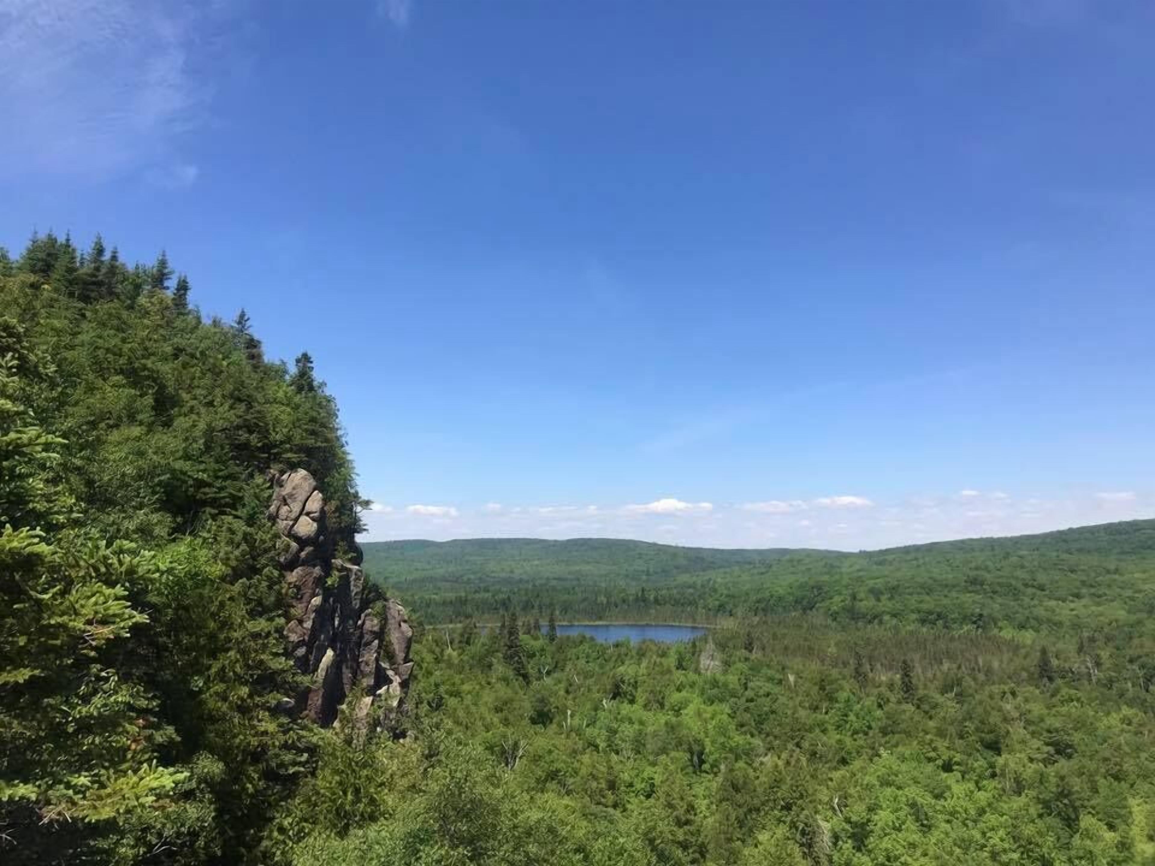 A mountainous landscape with dense forest and a lake.