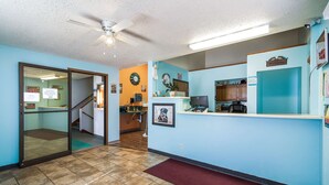 A reception area with a desk, a computer, and a clock on the wall. - The Roosevelt Hotel (Wibaux)