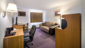 A hotel room with a desk, chair, sofa, and two lamps. - The Roosevelt Hotel (Wibaux)