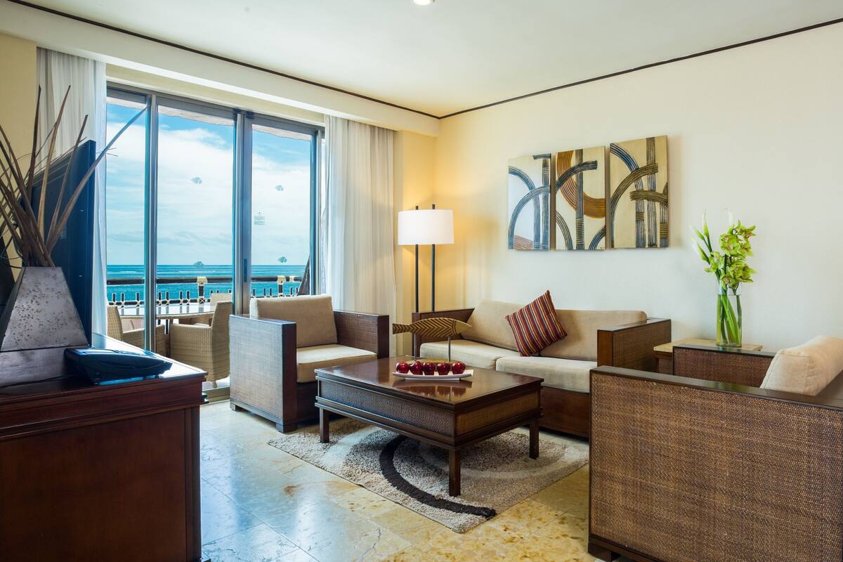 A modern living room with a sofa, armchairs, a coffee table, and artwork on the wall.