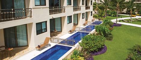 A hotel with multiple balconies, a swimming pool, and well-maintained gardens.