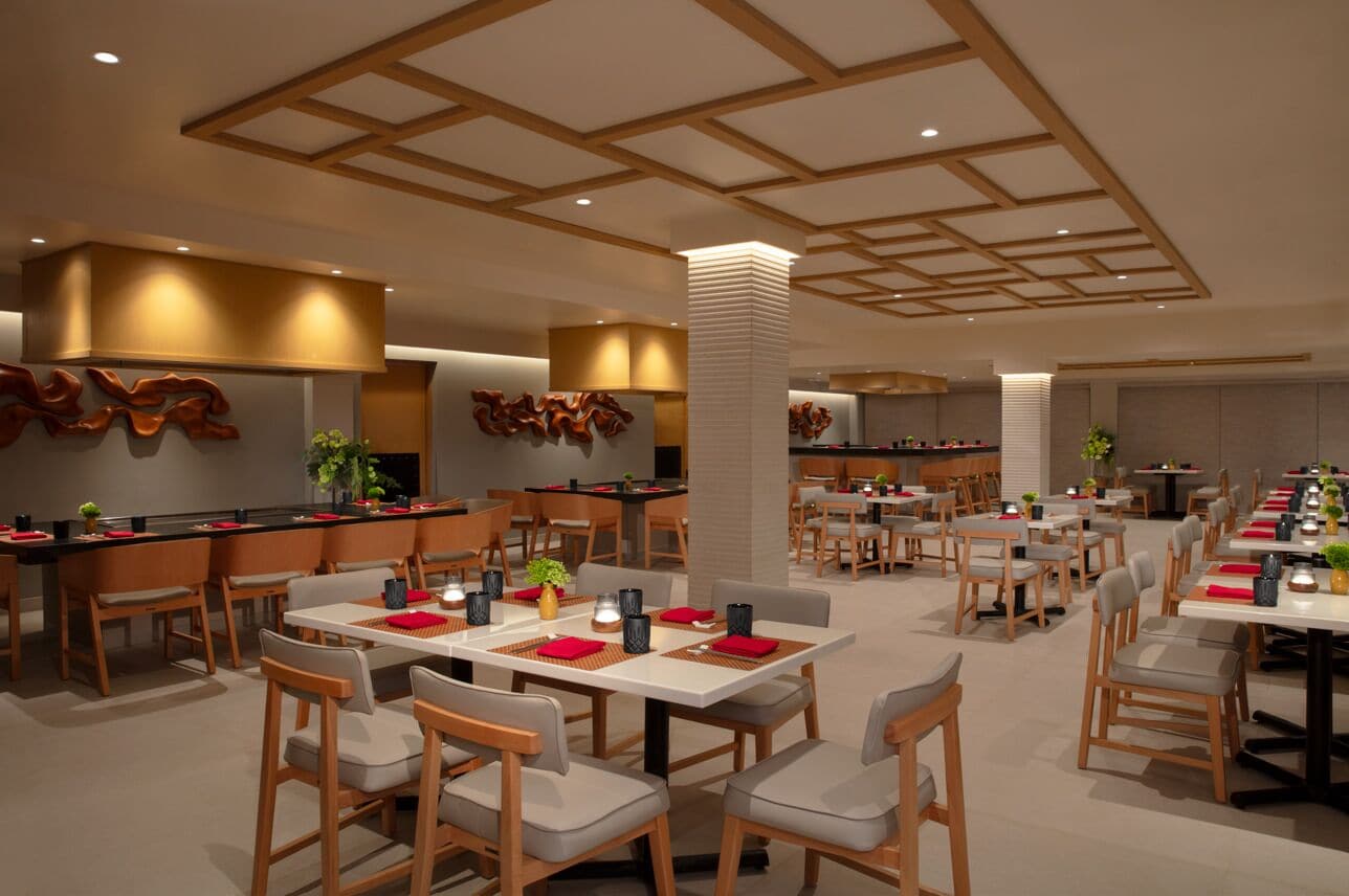 Un restaurant moderne avec des meubles en bois, une colonne centrale et un plafond avec des poutres en bois.