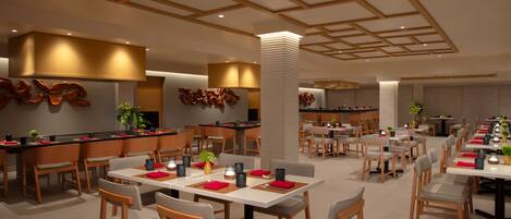 Un restaurant moderne avec des meubles en bois, une colonne centrale et un plafond avec des poutres en bois.