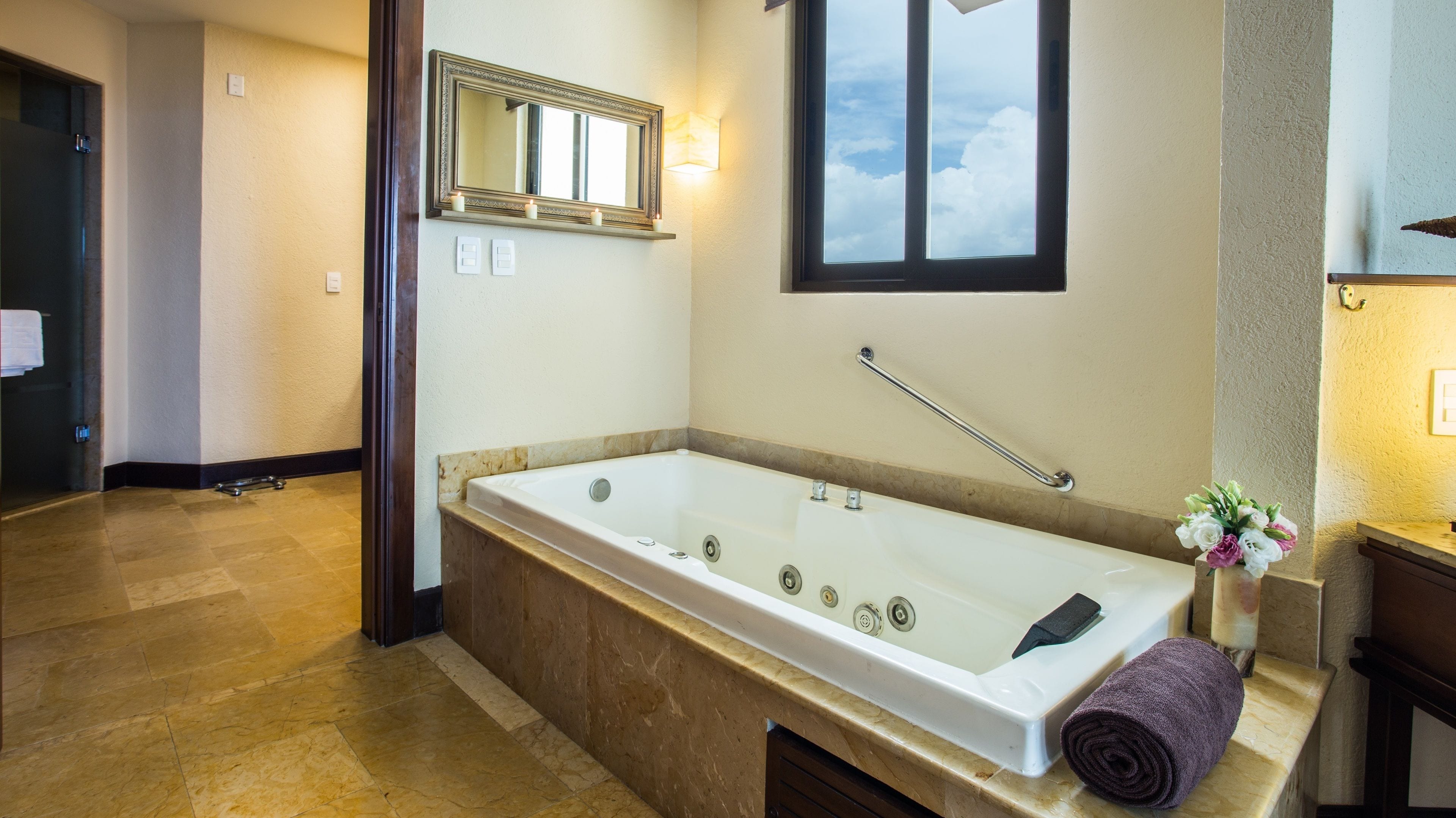 A modern bathroom with a large freestanding bathtub, a wall-mounted mirror, and a window providing natural light.