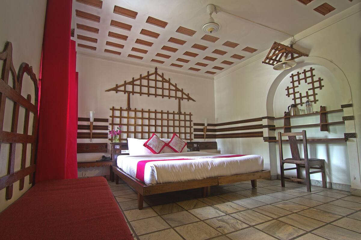 A bedroom with a wooden bed, a red accent wall, and a tiled floor.