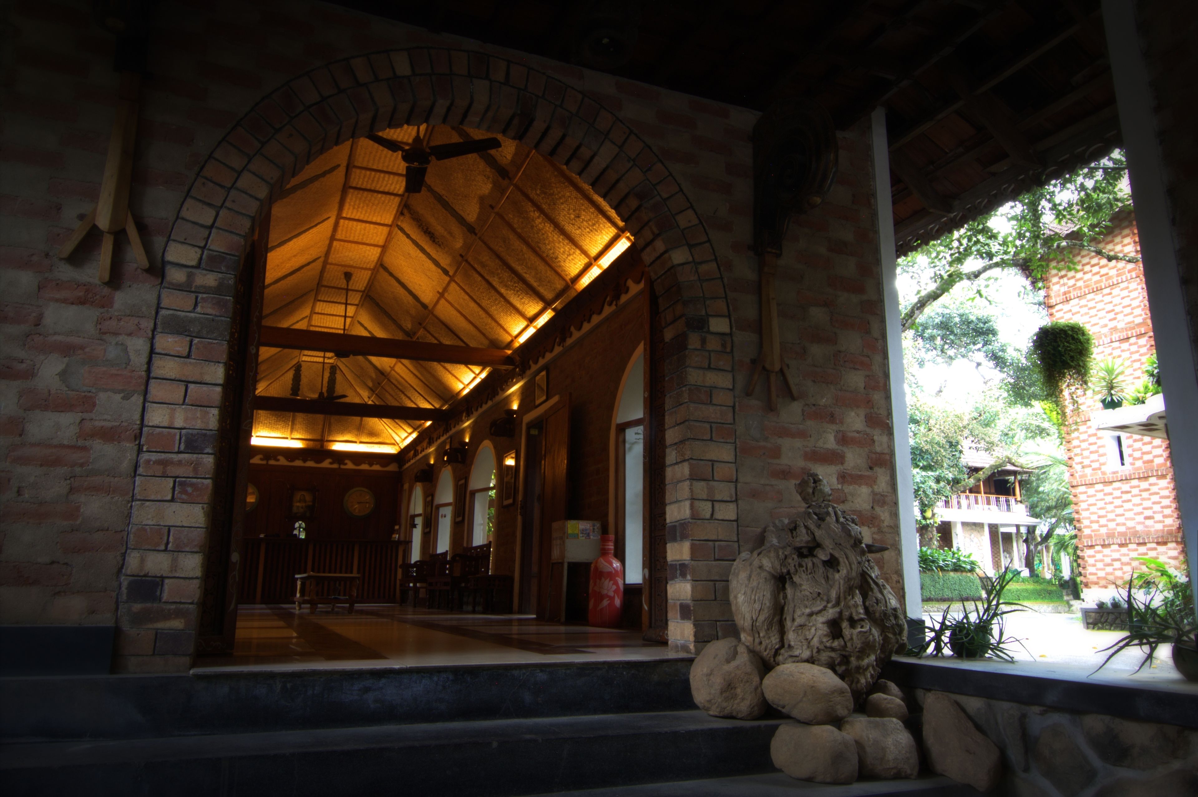 An arched brick entrance with a wooden ceiling and a ceiling fan.
