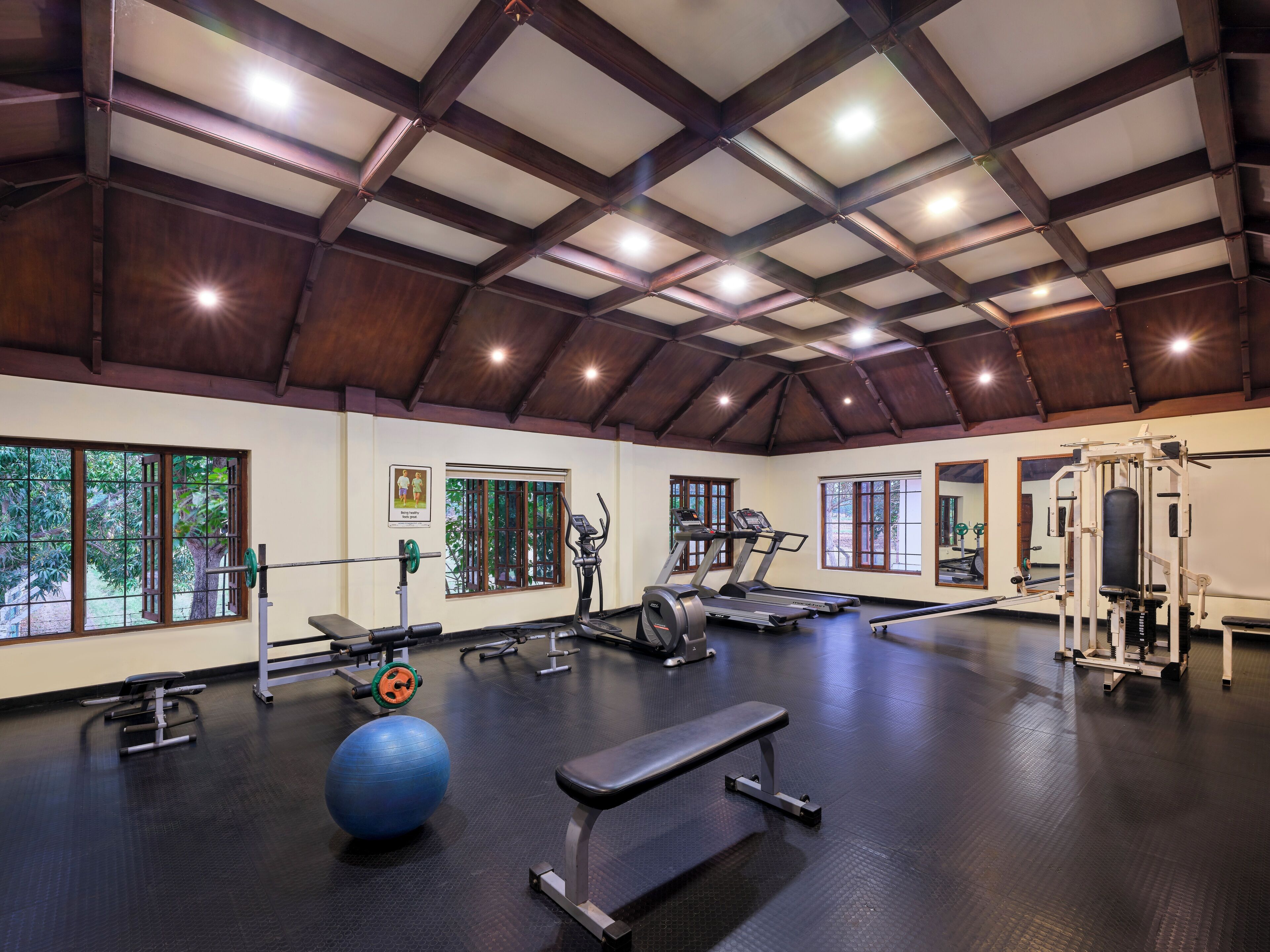 Un gimnasio con cintas de correr, máquinas de pesas, una banca y pelotas de ejercicio.