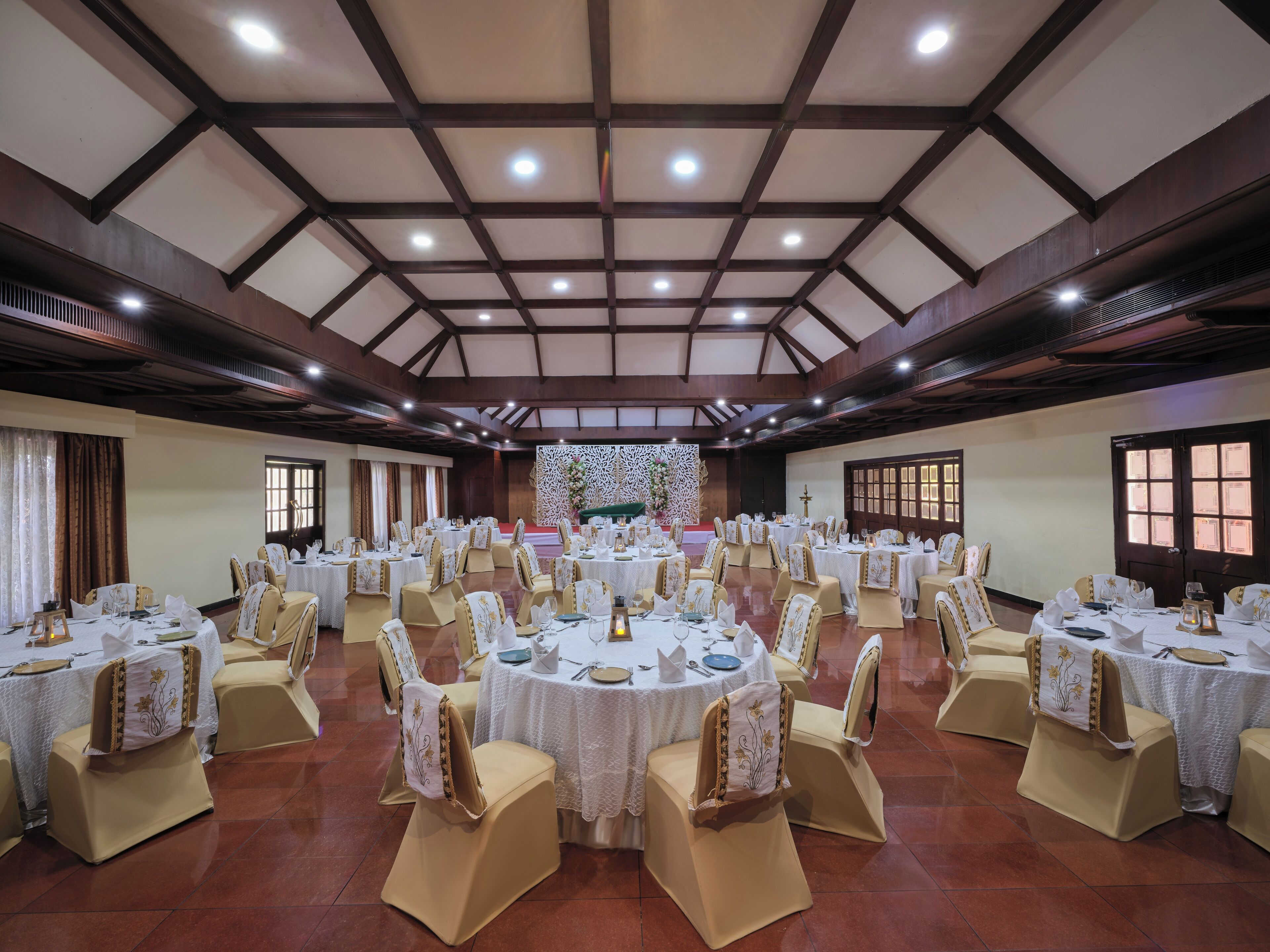 A banquet hall with round tables, chairs, and a stage.