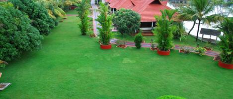 A resort with red-roofed buildings, lush green lawns, and palm trees.