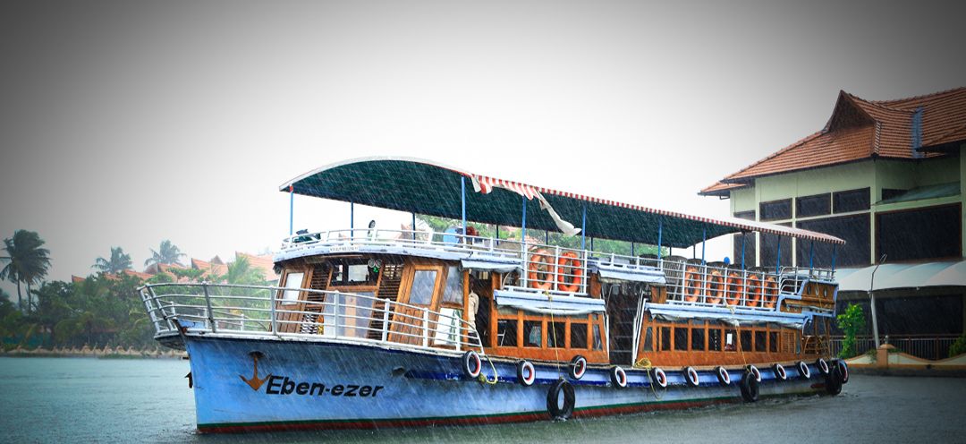 A large boat named 'Eben-ezer' docked near a building with a tiled roof.