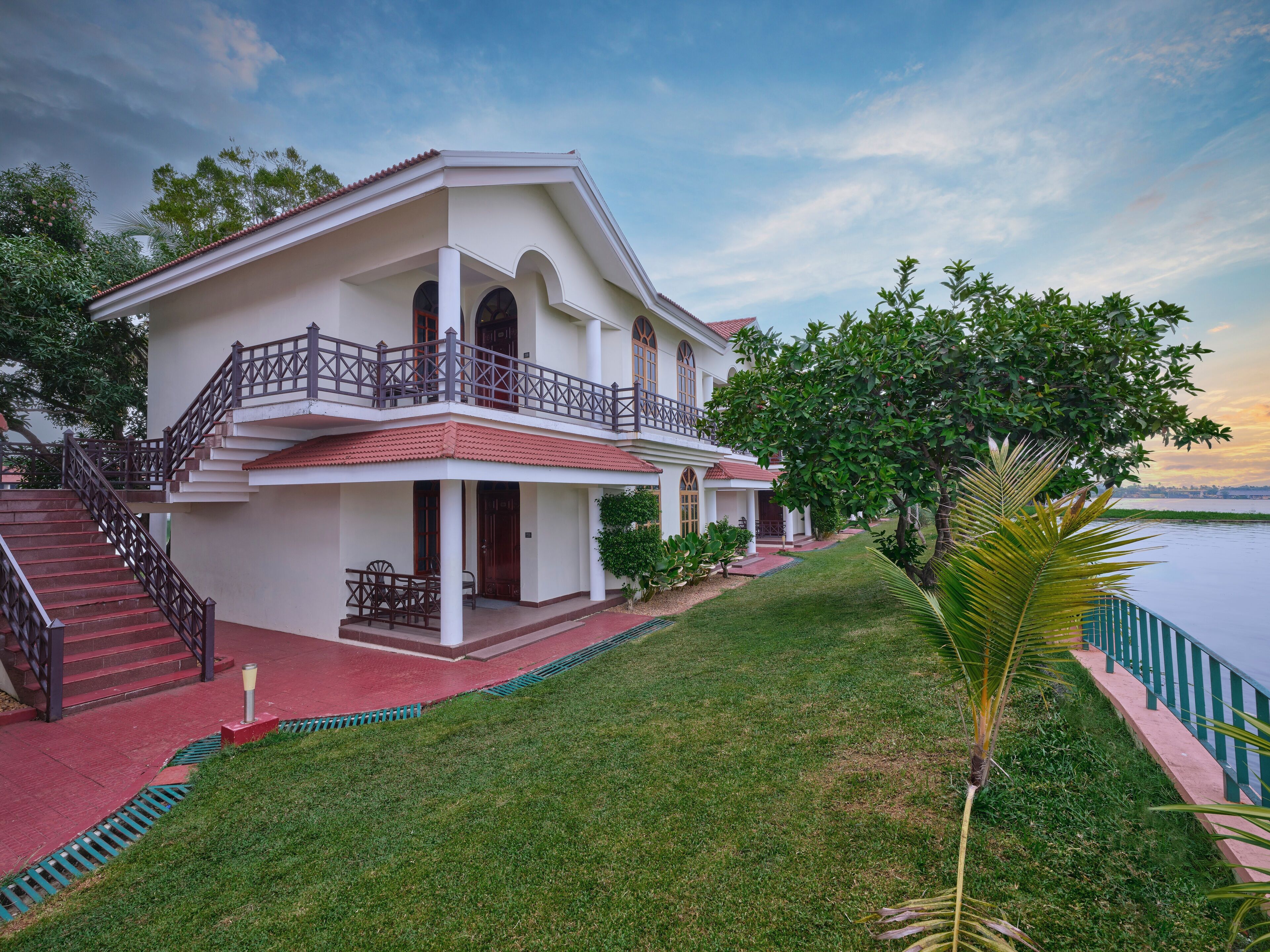 A two-story house with a balcony, a staircase, and a well-maintained lawn.