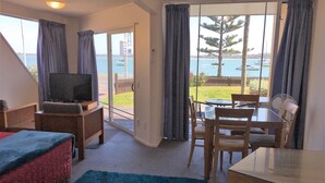 Una habitación con televisión, una mesa de comedor, sillas, un sofá y vista al mar.