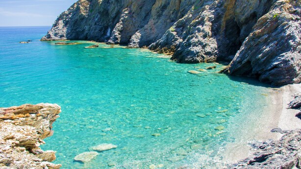 Un paisaje costero con aguas turquesas cristalinas, acantilados rocosos y una costa escarpada.