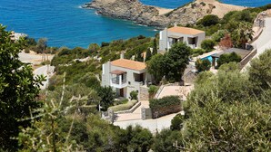 Una propiedad costera con dos casas modernas, una piscina y un promontorio rocoso en el mar.