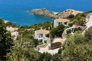 Ένα παραθαλάσσιο ακίνητο με δύο σύγχρονες κατοικίες, μια πισίνα και έναν βραχώδη όγκο που προεξέχει στη θάλασσα.