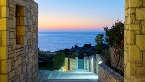 Un sendero de piedra que conduce a una puerta con vista al mar al atardecer.