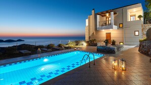 Un hotel moderno con piscina, mobiliario exterior y vistas al mar.