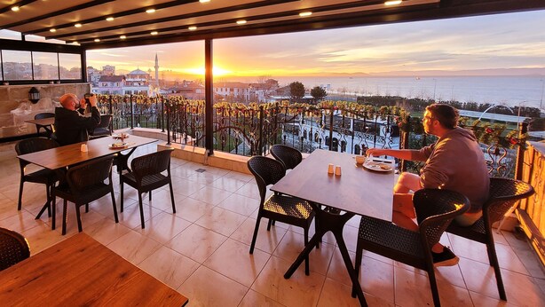 Un restaurant avec une terrasse offrant une vue sur le paysage urbain au coucher du soleil.