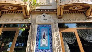 Un bâtiment sur lequel on peut lire l’inscription « HÔTEL SARUHAN », et sur lequel est également fixée, sous l’entrée, une décoration en forme de mosaïque représentant des motifs floraux.