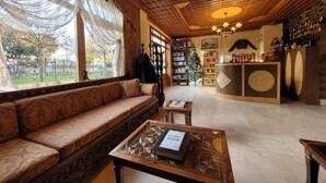 Un hall d’entrée accueillant, avec un banc en bois, une table basse sur laquelle repose un livre encadré, et une bibliothèque remplie de livres.