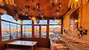 Un restaurant au décor intérieur en bois, avec une longue table et une variété de plats présentés sur un comptoir.