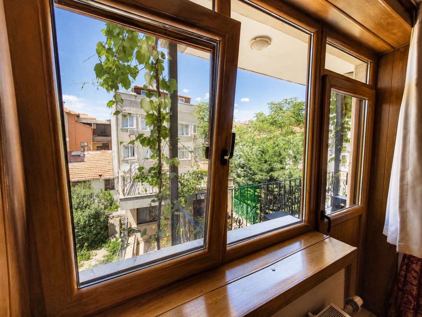 A room with a large window overlooking a residential area with buildings and greenery.