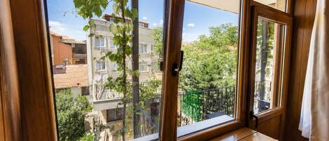 A room with a large window overlooking a residential area with buildings and greenery.