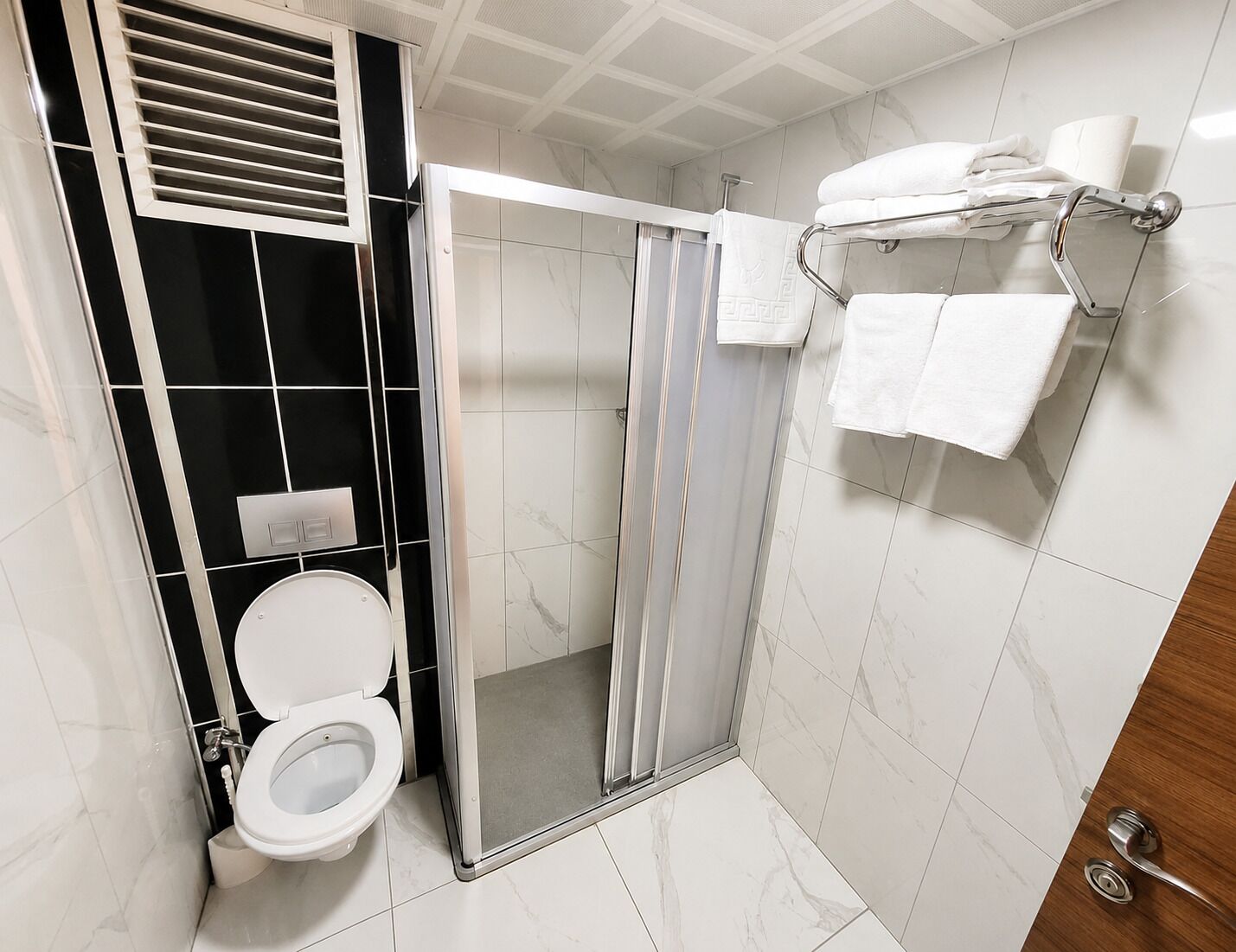 A modern bathroom with a toilet, shower, and towel rack.