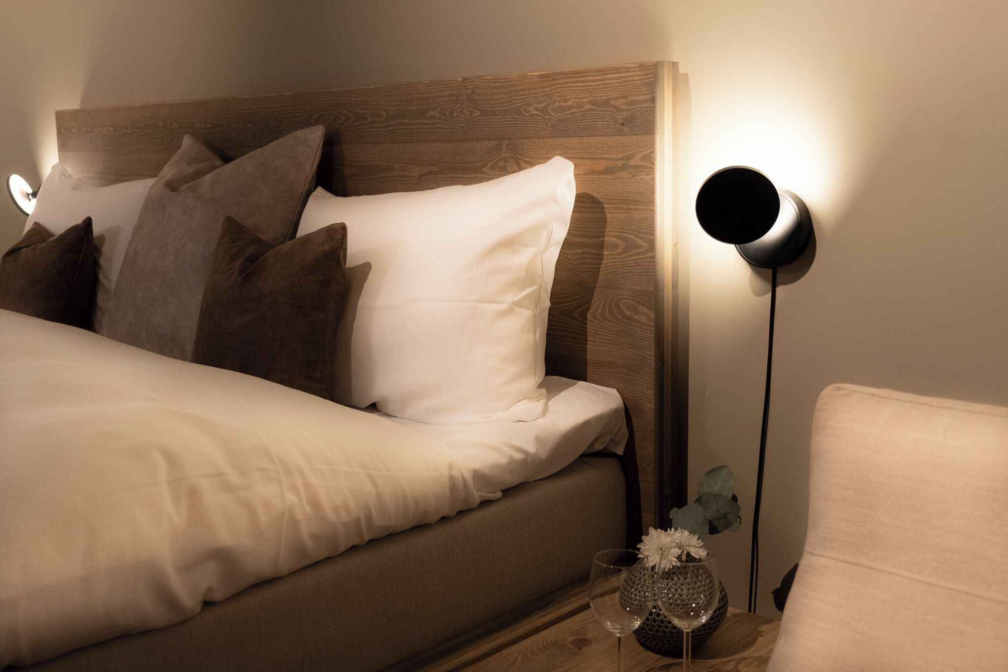 A neatly made bed with white and brown bedding, a wooden headboard, and a bedside lamp.