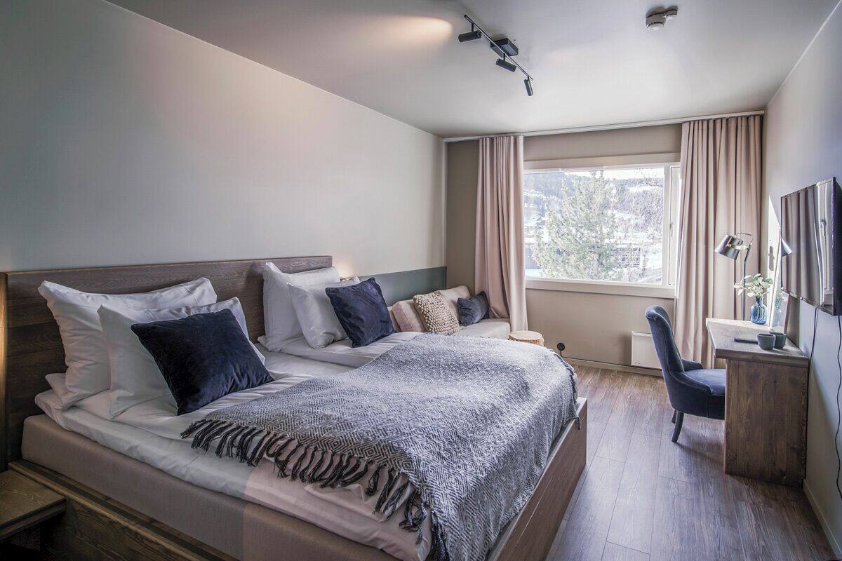 Ein modernes Hotelzimmer mit einem großen Bett, einem Schreibtisch und einem Stuhl.