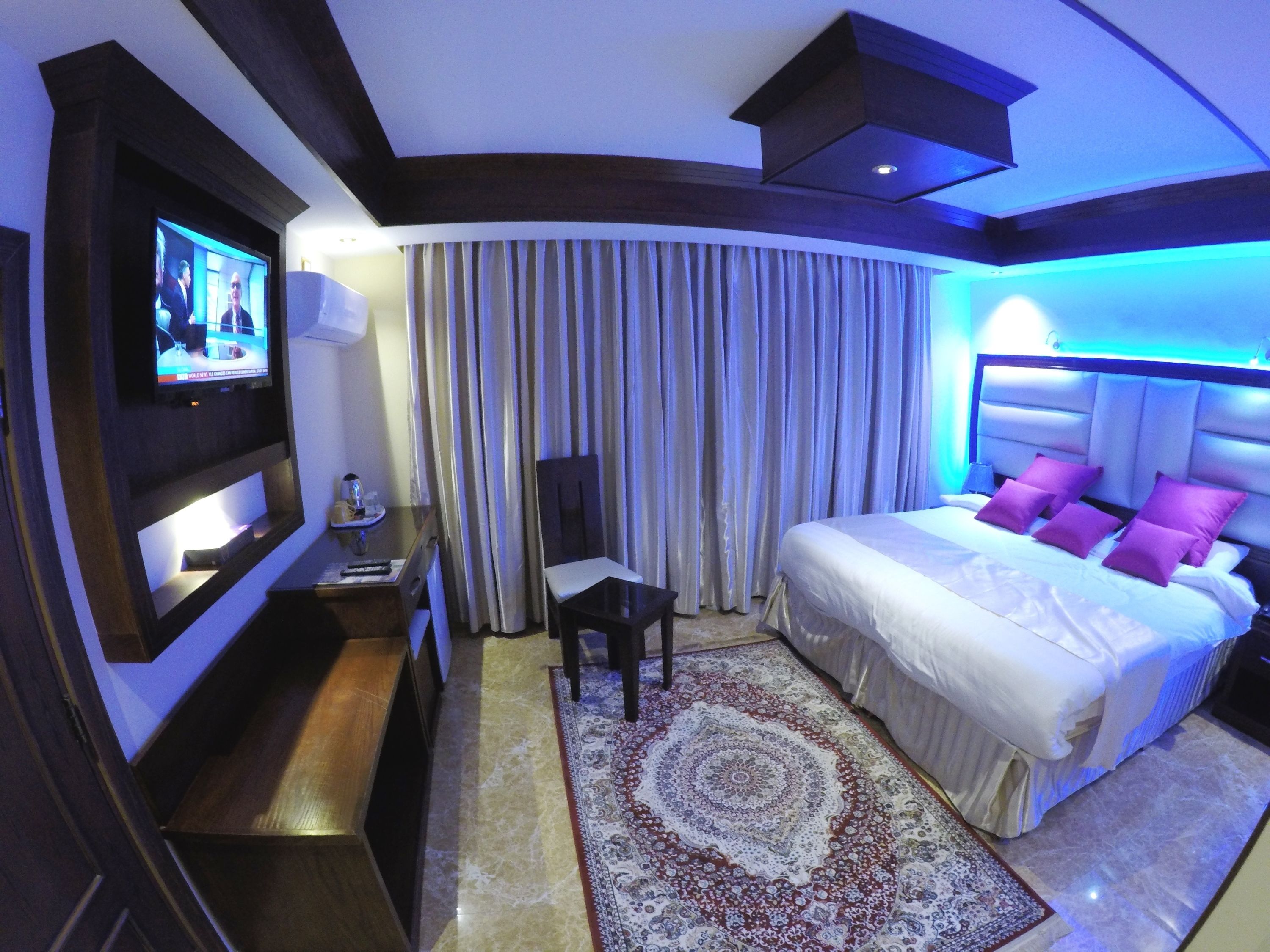 Une chambre d’hôtel avec un lit, une télévision, un bureau et une chaise.