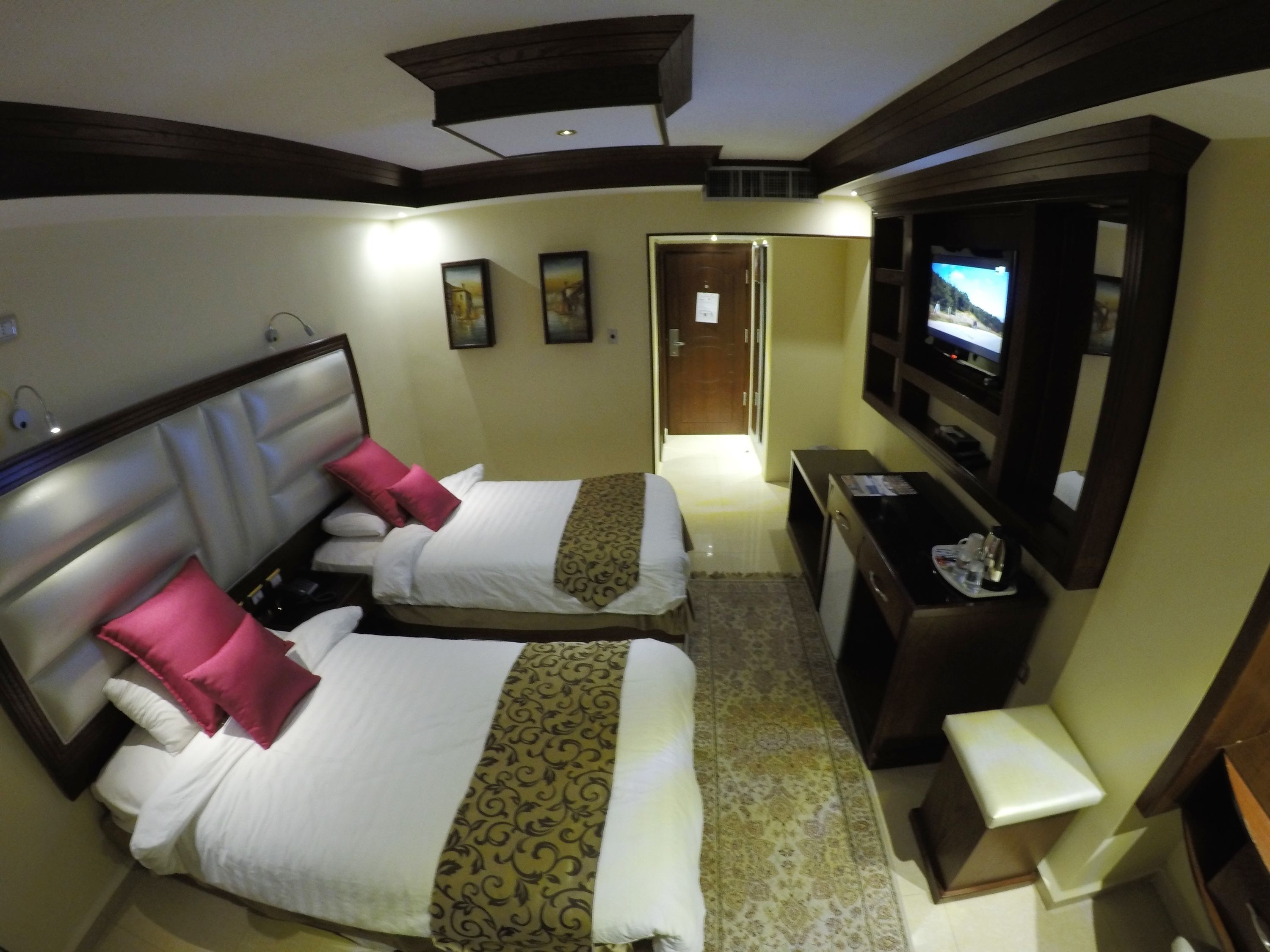 Una habitación de hotel con dos camas, televisión, escritorio y espejo.