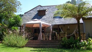 A house with a covered patio, steps leading to a door, and a hammock. - Mongoose Manor (Gqeberha (Port Elizabeth))