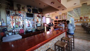 A bar area with a counter, stools, and a television screen. - The Pink Palace (Corfu)
