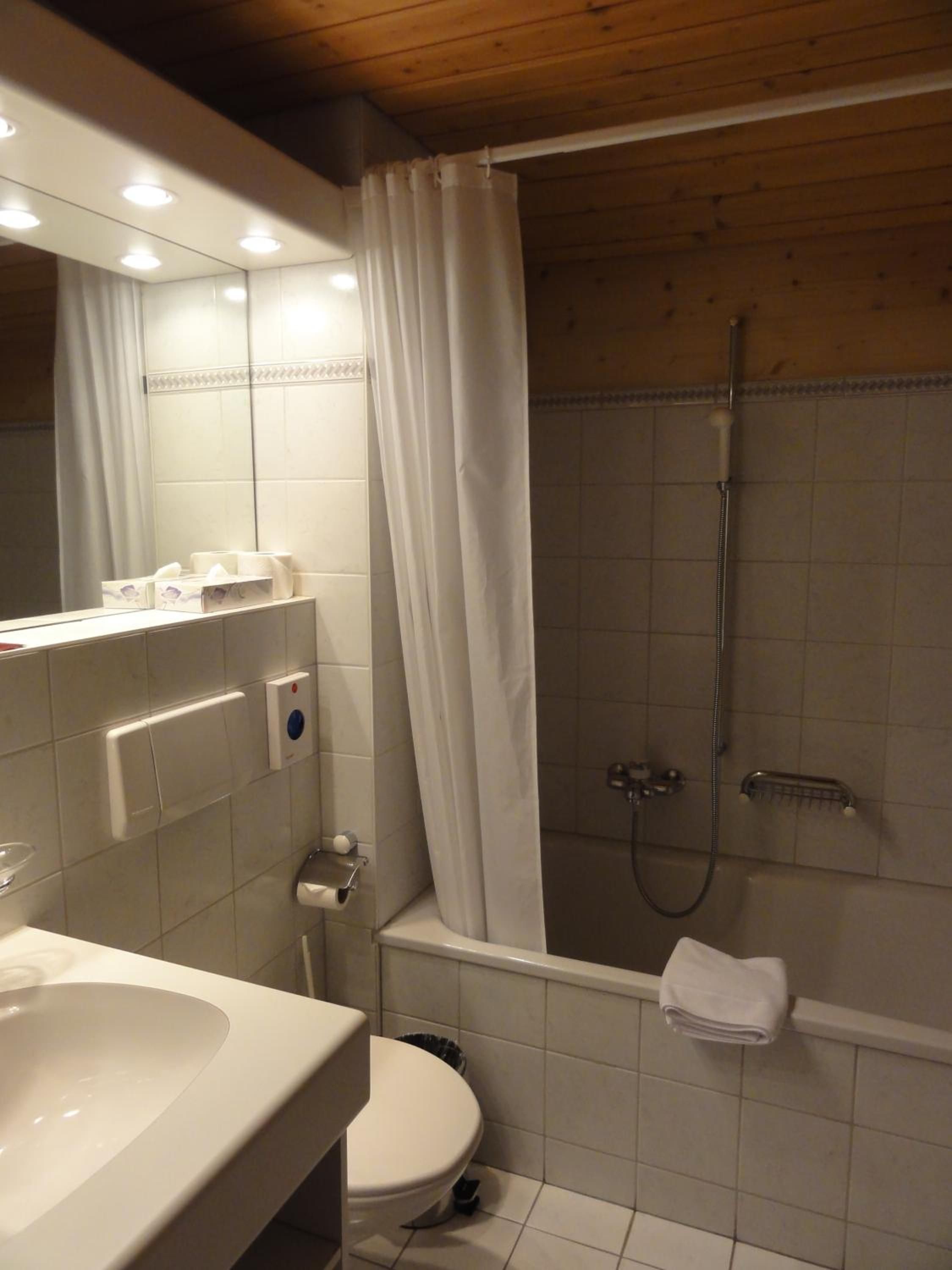 A bathroom with a white sink, toilet, and shower area.