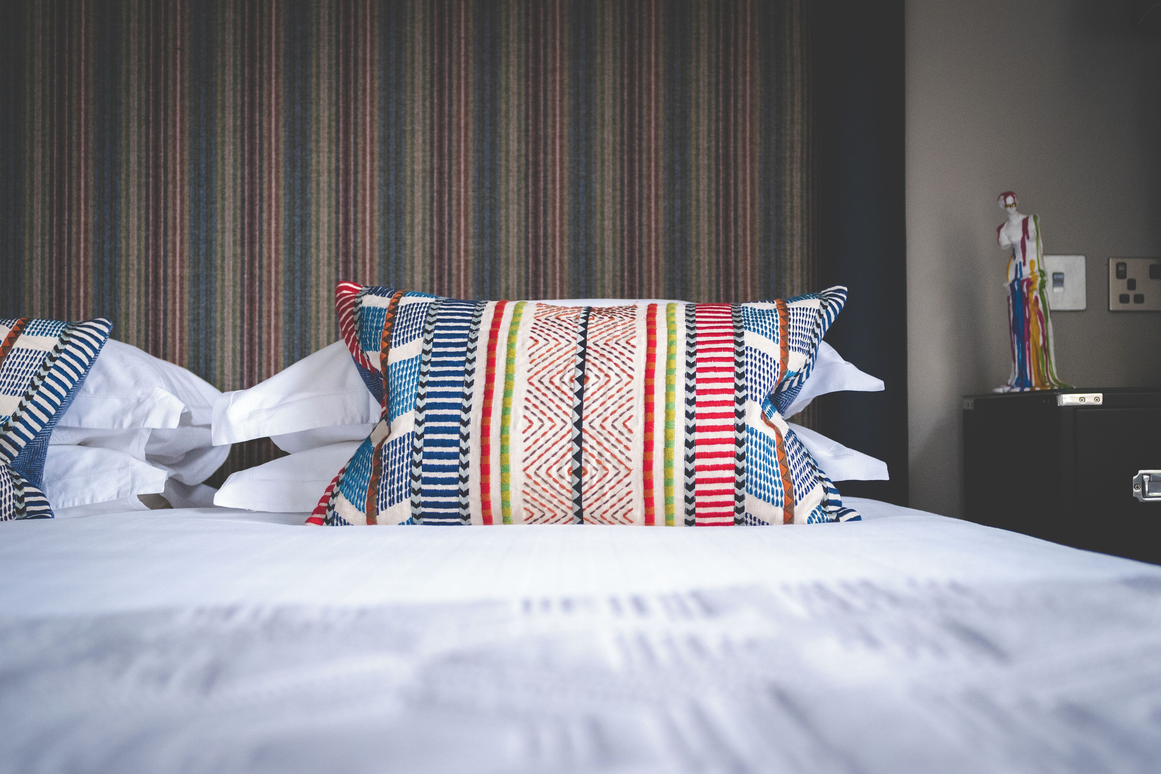 A bed with patterned pillows and a striped headboard.