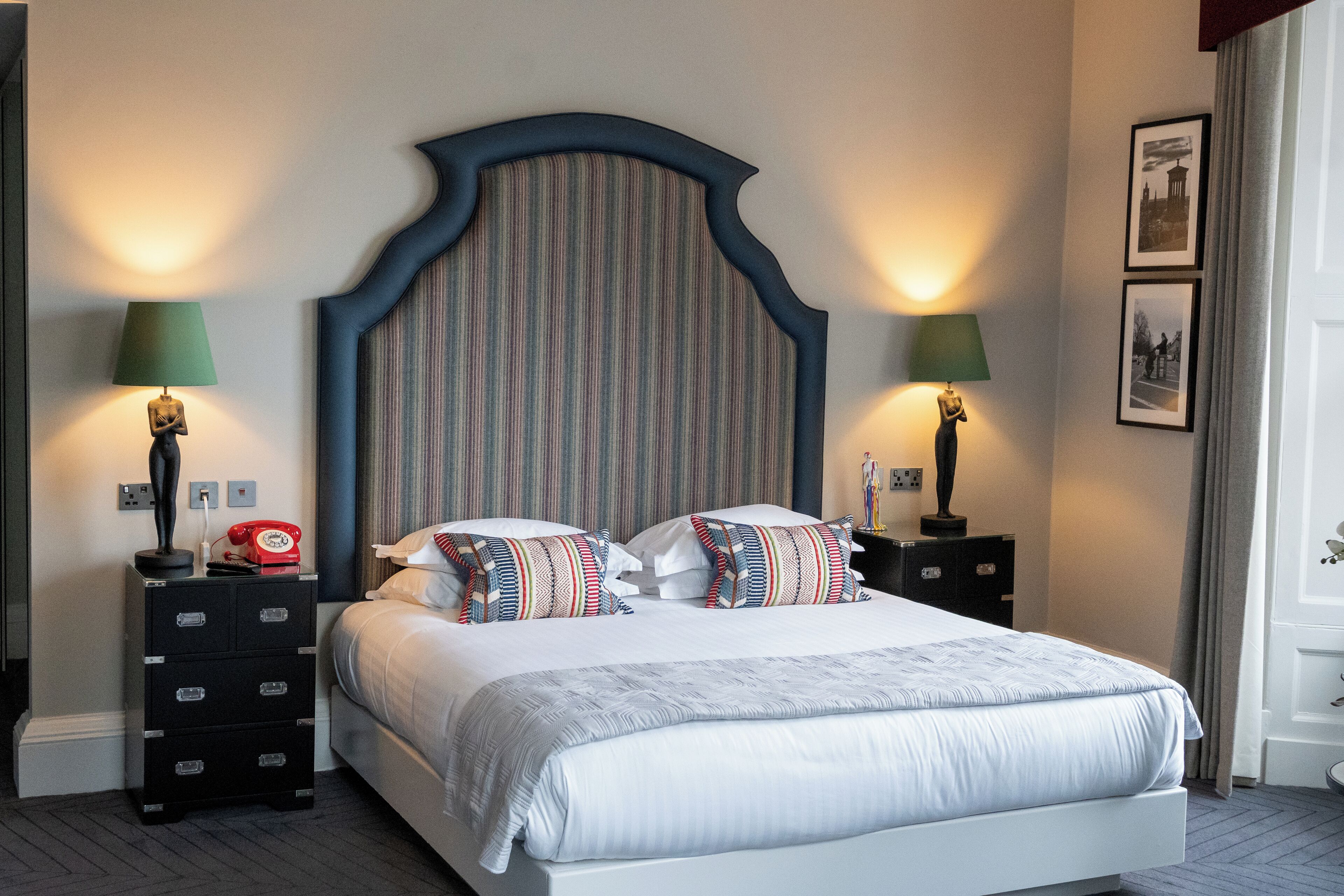 A neatly made bed with striped bedding, two bedside tables with lamps, and a headboard.