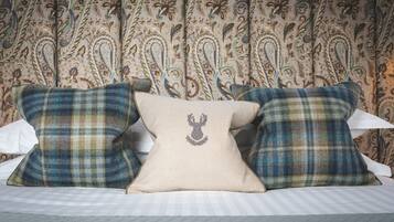 Una cama con tres almohadas, una con diseño de cabeza de ciervo, y una cortina estampada al fondo.