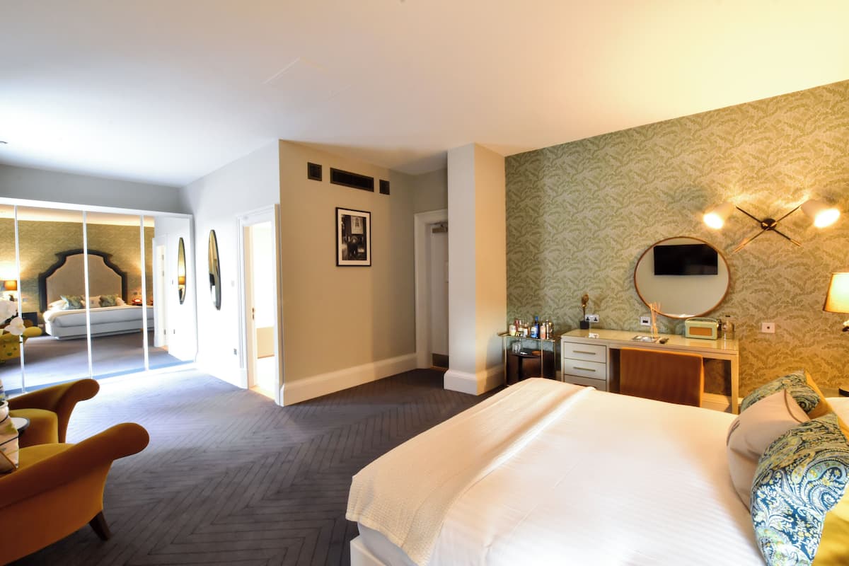 A hotel room with a bed, a desk, a chair, a mirror, and a wardrobe.